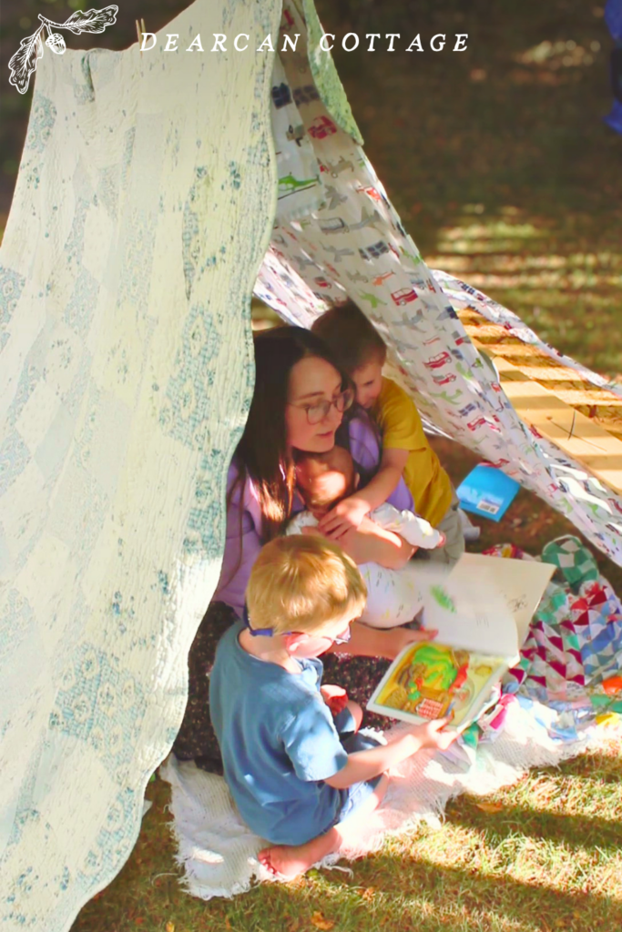 Reading in a blanket fort tent in the backyard